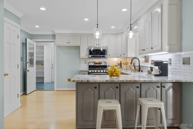 kitchen with white cabinetry, appliances with stainless steel finishes, decorative light fixtures, and kitchen peninsula