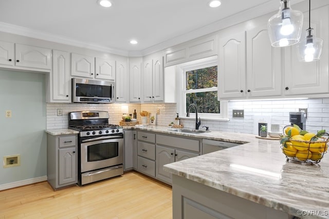 kitchen with pendant lighting, sink, stainless steel appliances, light stone counters, and white cabinets