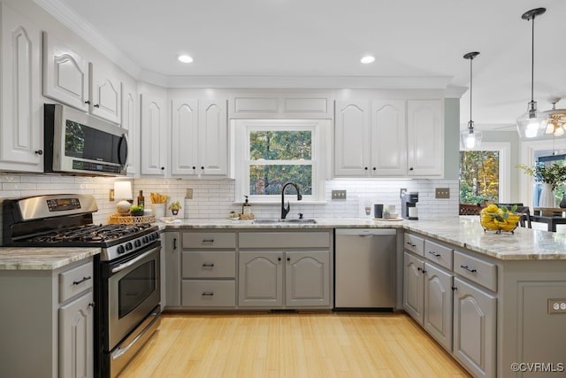 kitchen featuring appliances with stainless steel finishes, sink, gray cabinetry, hanging light fixtures, and kitchen peninsula