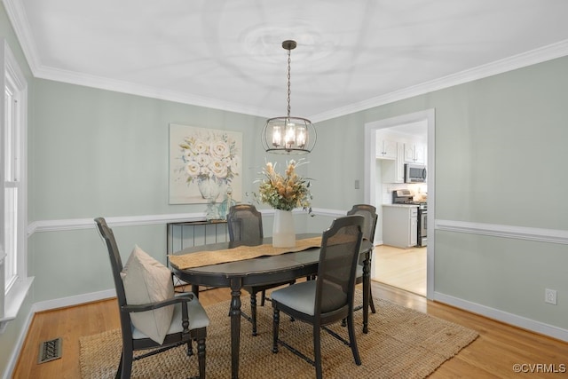 dining room featuring crown molding, light hardwood / wood-style floors, and a notable chandelier