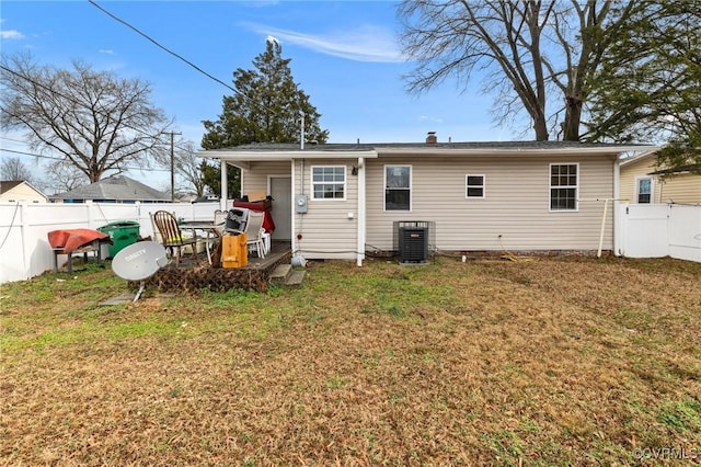 rear view of property with a lawn and central air condition unit