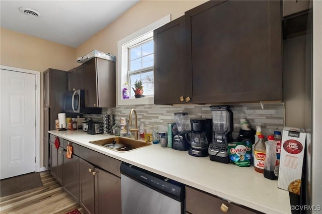 kitchen with dark brown cabinetry, sink, dishwasher, light hardwood / wood-style floors, and decorative backsplash