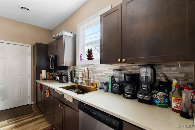 kitchen featuring tasteful backsplash, sink, dark brown cabinets, and stainless steel dishwasher