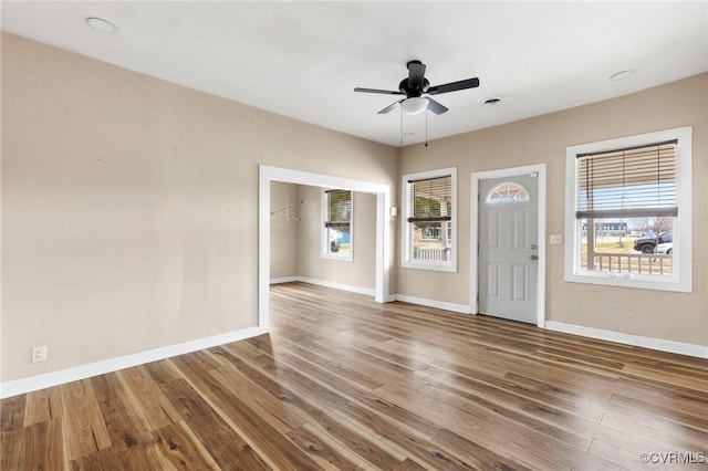 foyer with a ceiling fan, a wealth of natural light, baseboards, and wood finished floors