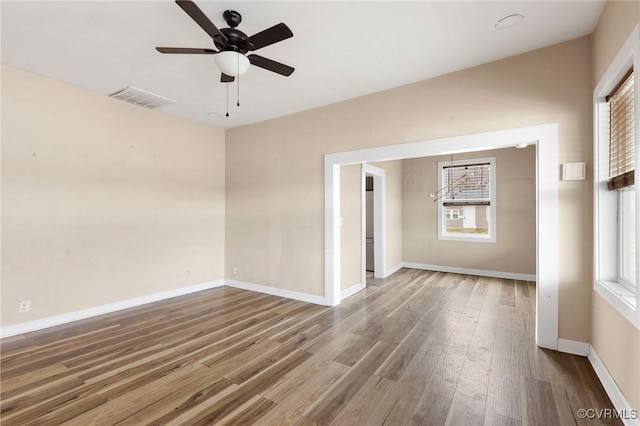 spare room with a healthy amount of sunlight, visible vents, baseboards, and wood finished floors