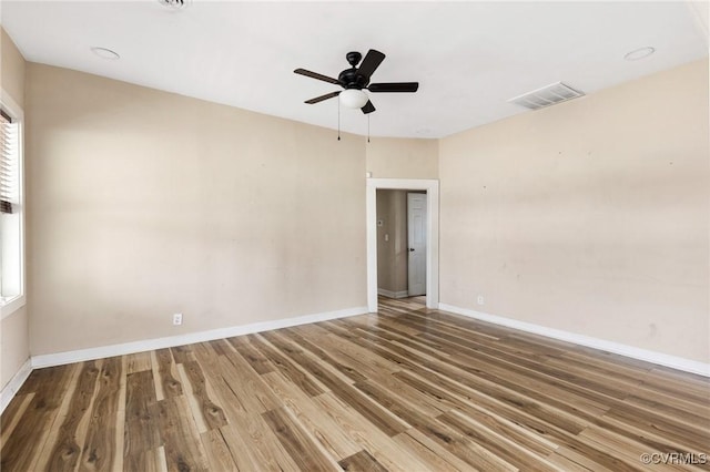 spare room featuring a ceiling fan, wood finished floors, visible vents, and baseboards