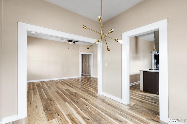 empty room featuring light wood finished floors, ceiling fan, and baseboards