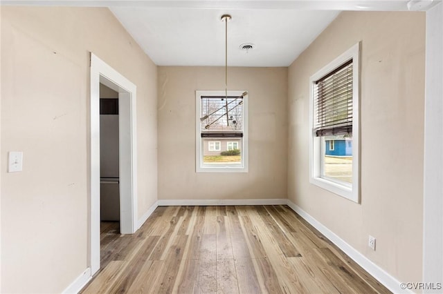 unfurnished dining area featuring baseboards, visible vents, and light wood finished floors