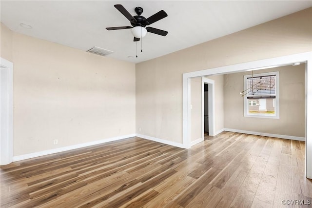 spare room with baseboards, visible vents, ceiling fan, and wood finished floors