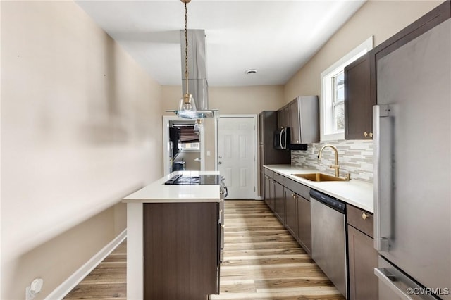 kitchen with light wood-style flooring, a sink, stainless steel dishwasher, backsplash, and a center island