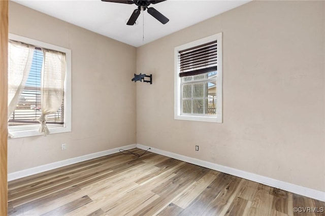 spare room featuring plenty of natural light, baseboards, and wood finished floors