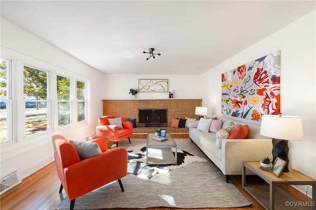 living room featuring a brick fireplace and light wood-type flooring