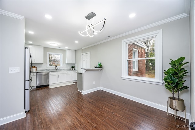 kitchen featuring crown molding, decorative light fixtures, white cabinets, and appliances with stainless steel finishes