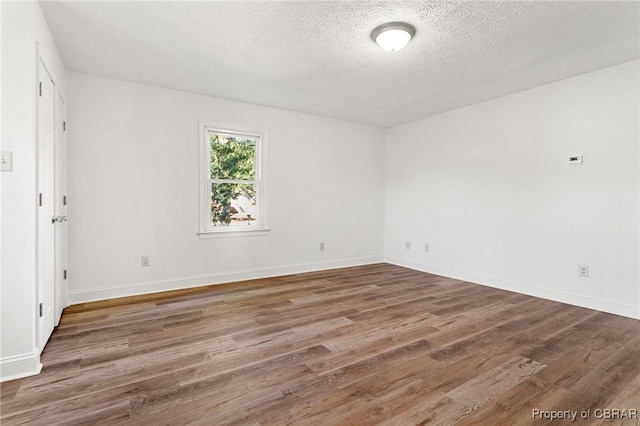 spare room with dark hardwood / wood-style floors and a textured ceiling