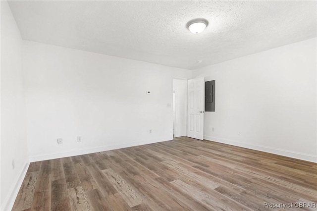 unfurnished room featuring wood-type flooring, electric panel, and a textured ceiling