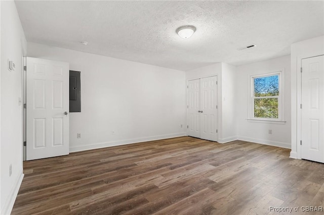 unfurnished bedroom with dark wood-type flooring, electric panel, and a textured ceiling