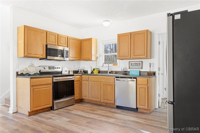 kitchen with appliances with stainless steel finishes, sink, and light wood-type flooring