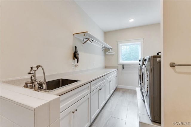 laundry room featuring washer and dryer, sink, and cabinets