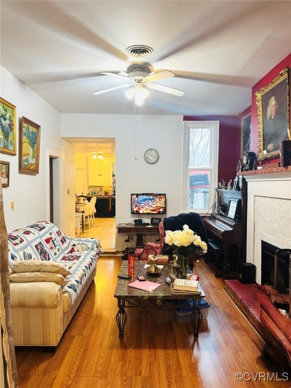 living room with hardwood / wood-style flooring, ceiling fan, and a fireplace