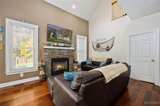 living room with high vaulted ceiling, a stone fireplace, and dark hardwood / wood-style floors