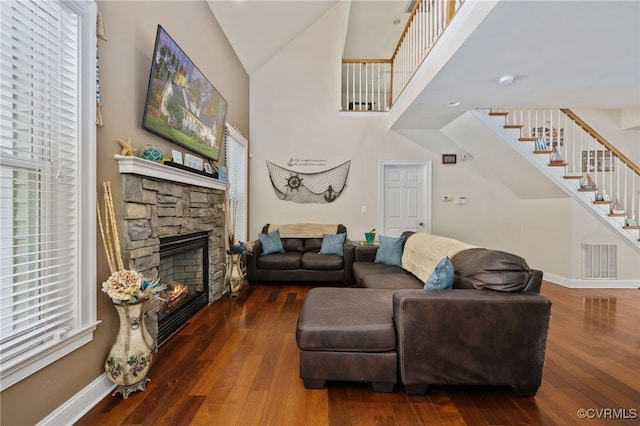 living room featuring a fireplace, dark wood-type flooring, and a towering ceiling