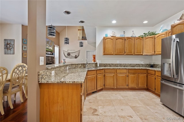 kitchen with light stone countertops, pendant lighting, sink, stainless steel fridge with ice dispenser, and kitchen peninsula