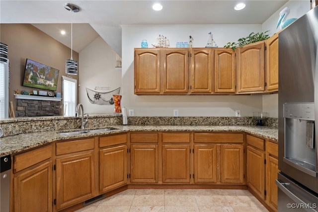 kitchen with appliances with stainless steel finishes, hanging light fixtures, light stone countertops, light tile patterned floors, and sink