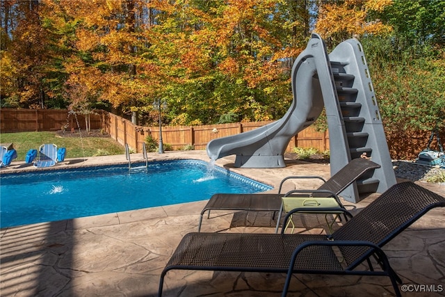 view of pool with a patio area, pool water feature, and a water slide