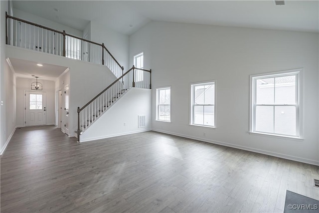 unfurnished living room with hardwood / wood-style floors, a towering ceiling, and a wealth of natural light