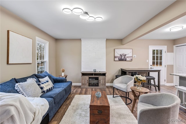 living room with a large fireplace and dark hardwood / wood-style flooring