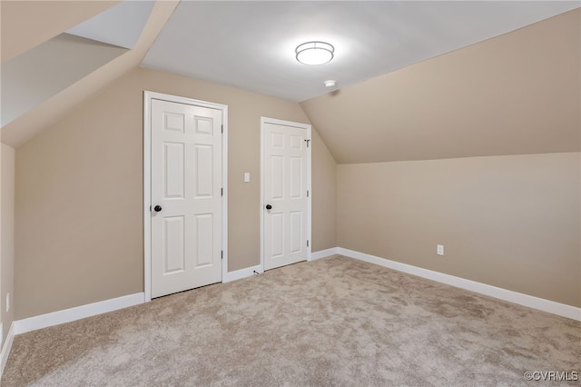 bonus room with lofted ceiling and light carpet