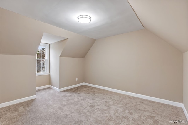 additional living space featuring vaulted ceiling and light carpet