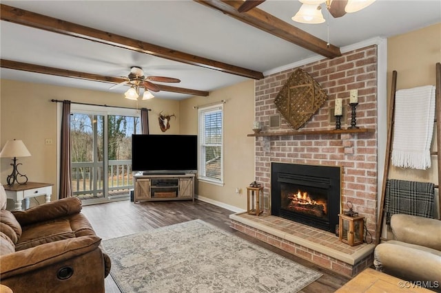 living room featuring a fireplace, beam ceiling, dark wood-type flooring, and ceiling fan