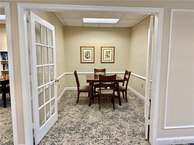 dining space featuring french doors, a paneled ceiling, carpet, and baseboards