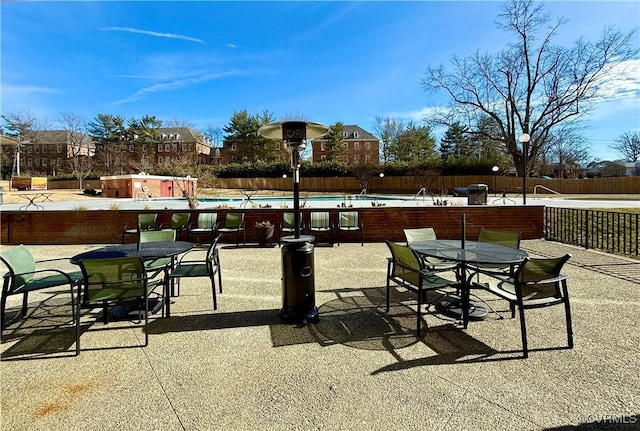 view of patio / terrace featuring outdoor dining space, a community pool, and fence