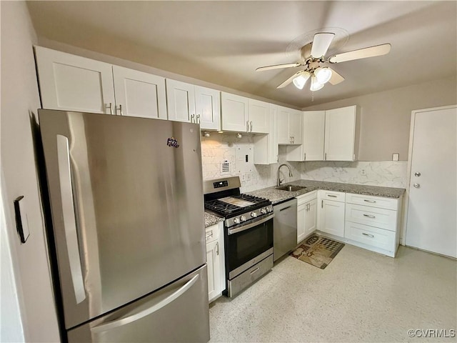 kitchen featuring light stone countertops, a sink, stainless steel appliances, white cabinets, and backsplash