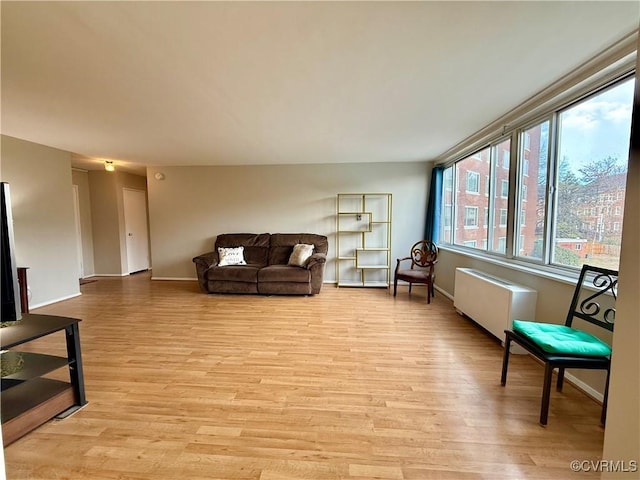 living area with baseboards, radiator, and light wood-style flooring