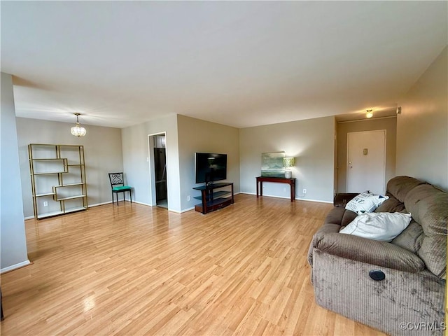 living room featuring an inviting chandelier, baseboards, and light wood-type flooring