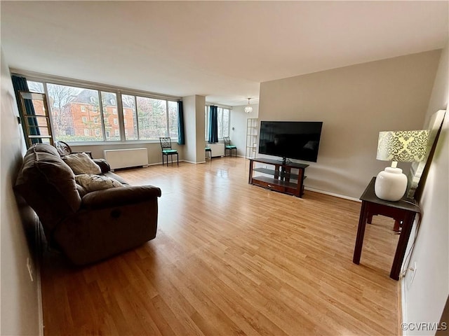 living area featuring light wood-type flooring, baseboards, and radiator heating unit