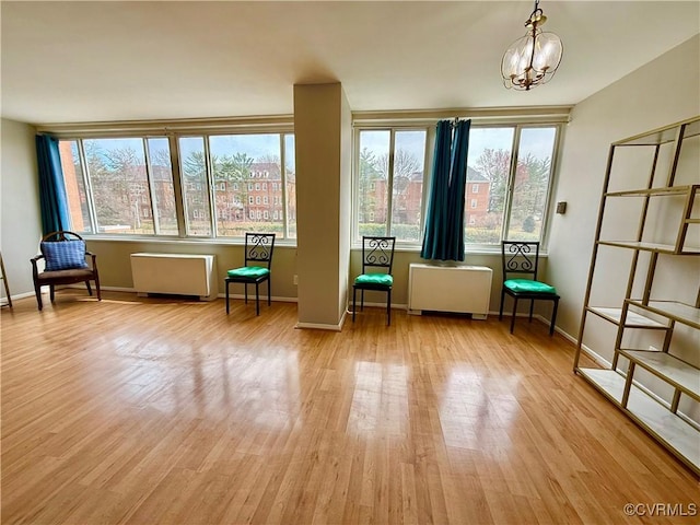 unfurnished room with a chandelier, radiator, baseboards, and wood finished floors