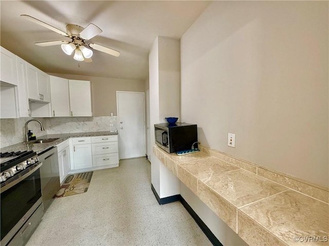 kitchen with decorative backsplash, white cabinets, appliances with stainless steel finishes, and a sink