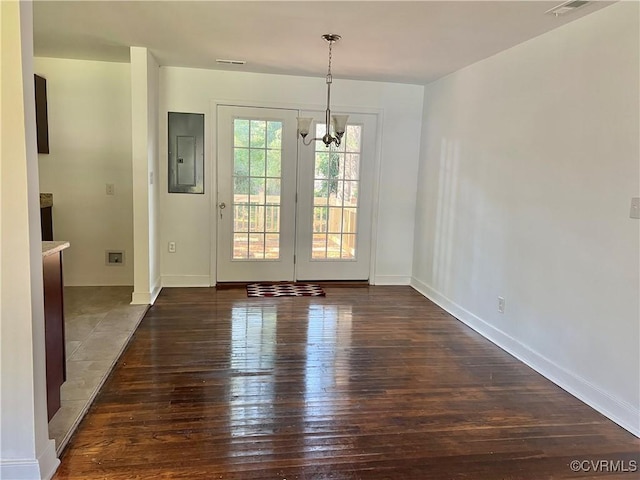 unfurnished dining area featuring dark hardwood / wood-style flooring, electric panel, and a chandelier