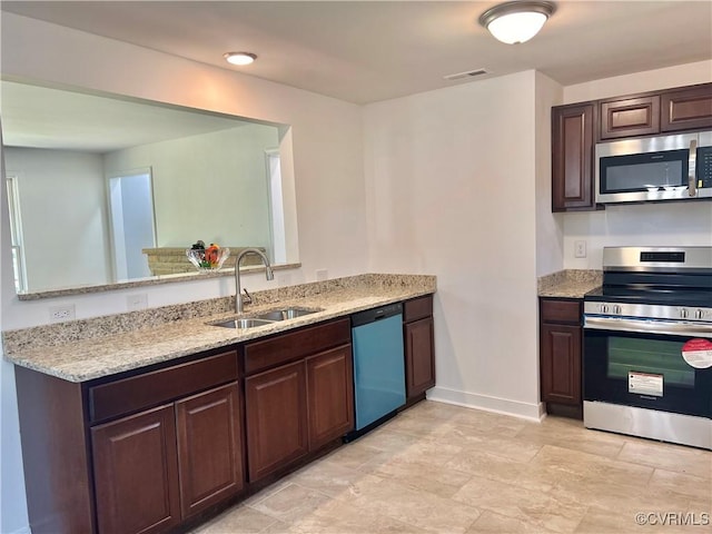 kitchen featuring dark brown cabinetry, stainless steel appliances, light stone countertops, and sink