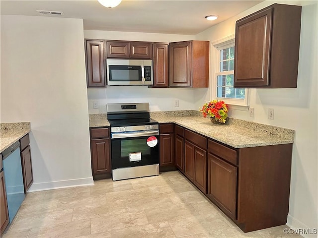 kitchen featuring appliances with stainless steel finishes, light stone countertops, and dark brown cabinets