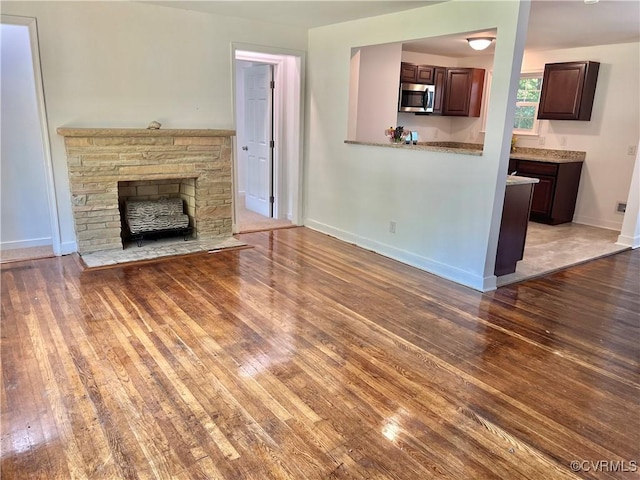 unfurnished living room with a stone fireplace and hardwood / wood-style floors