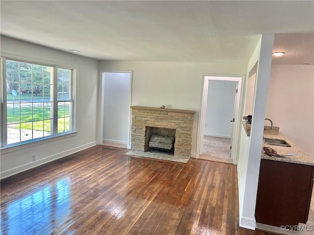 unfurnished living room with sink, a fireplace, and dark hardwood / wood-style flooring