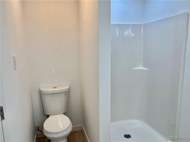 bathroom featuring walk in shower and toilet