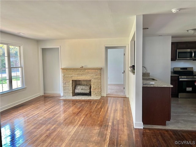 unfurnished living room with sink, a fireplace, and dark hardwood / wood-style floors