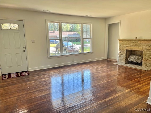 unfurnished living room featuring a stone fireplace and dark hardwood / wood-style flooring