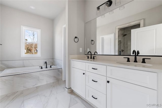 bathroom featuring a relaxing tiled tub and vanity